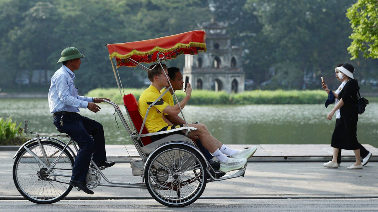 Tourists ride a cyclo around Hoan Kiem Lake