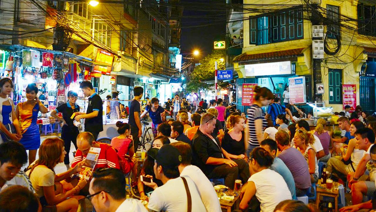 Tourists walking safely through busy Hanoi Beer Street at night