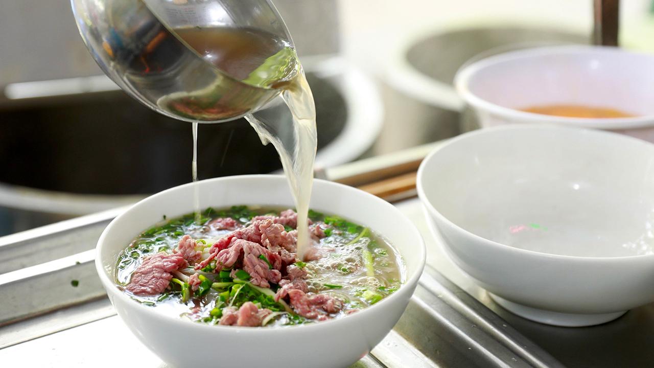 Tô phở Hà Nội truyền thống với nước dùng trong, thịt bò thái mỏng và rau thơm tươi.