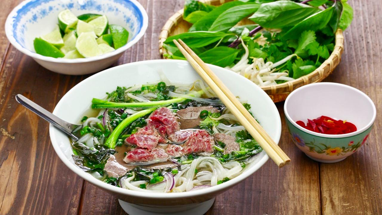 Đĩa rau thơm, chanh, ớt, và tương ớt ăn kèm phở Hà Nội.